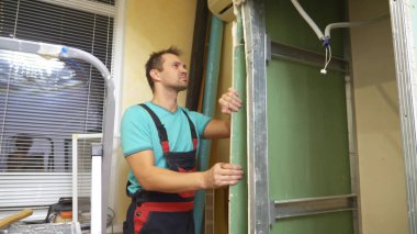 Ev geliştirme. Bir adam bir odada alçıpan kemerini söker.