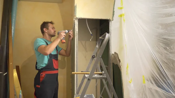 Улучшения дома. мужчина разбирает арку гипсокартона в комнате — стоковое фото