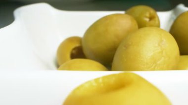 Yakın plan, detaylı. Beyaz tabakta yeşil zeytin.