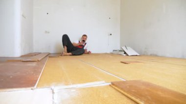 Yenileme odasındaki tamirci akıllı telefon kullanarak yerde yatıyor.