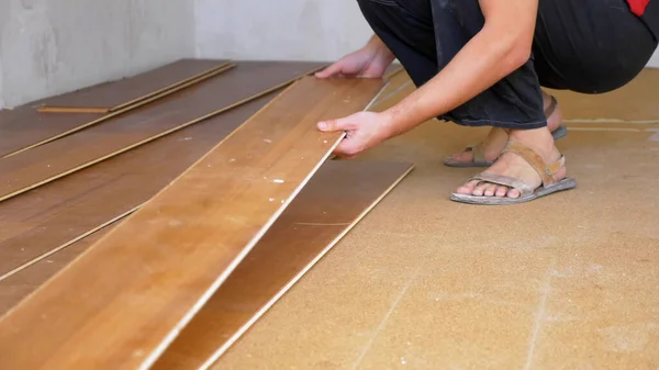 Close-up. construtor masculino quebra o piso laminado velho no apartamento — Fotografia de Stock