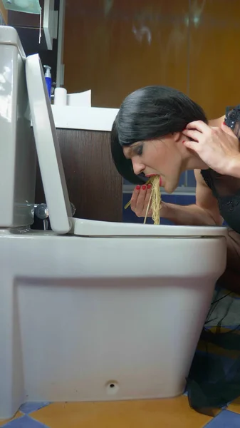 Verticalmente. un hombre disfrazado de mujer comiendo fideos del baño — Foto de Stock