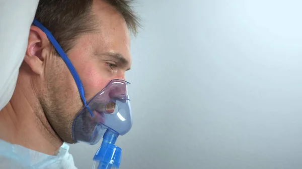 Portrait of a man in an oxygen mask who lies on a bed in a hospital — Stock Photo, Image