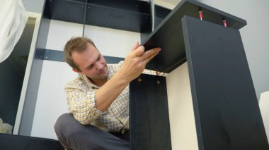 Yakışıklı adam evde mobilya koleksiyonu yapıyor. Boşluğu kopyala