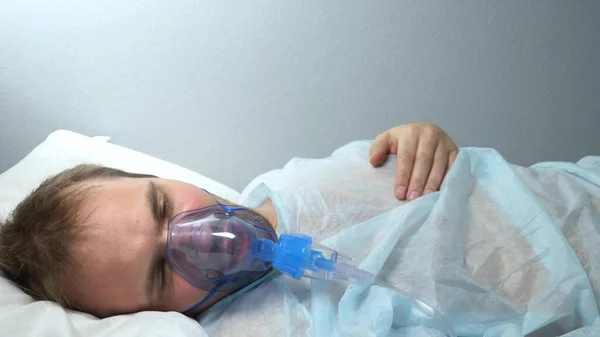 Potret seorang pria dengan masker oksigen yang terbaring di tempat tidur di rumah sakit — Stok Foto