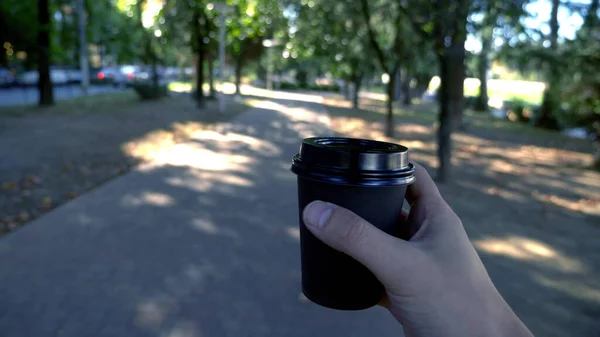 한 남자가 손에 일회용 커피를 들고 길을 걷고 있다 — 스톡 사진