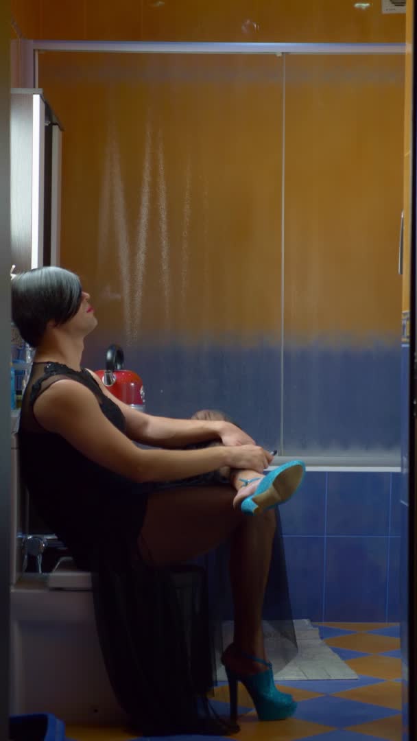 Vertical. a man dressed as a woman sits on the toilet and smokes a cigarette — Stock Video