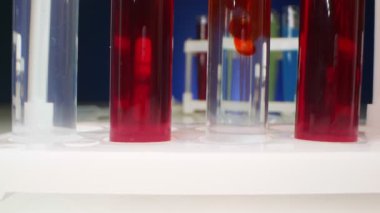  Kimyasal deneyler. Kırmızı sıvı, test tüpündeki temiz bir sıvıda çözünür.