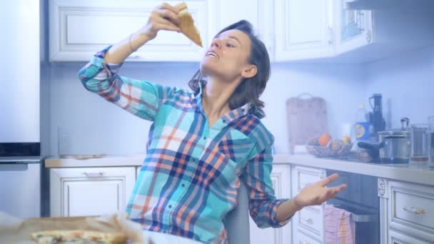 Alegre divertida mujer comiendo pizza fuera de la caja en casa en la cocina — Vídeos de Stock
