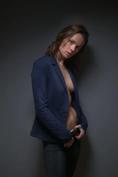 Wanita ramping cantik dalam jaket ketat pada tubuh telanjang. latar belakang abu-abu — Stok Foto