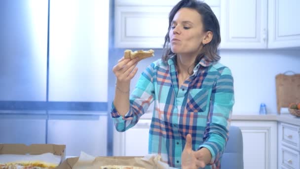 Alegre divertida mujer comiendo pizza fuera de la caja en casa en la cocina — Vídeos de Stock