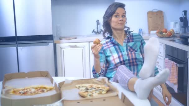 Alegre linda chica comer una manzana mientras está sentado en su cocina en casa — Vídeos de Stock