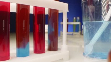  Kimyasal deneyler. Kırmızı sıvı, test tüpündeki temiz bir sıvıda çözünür.