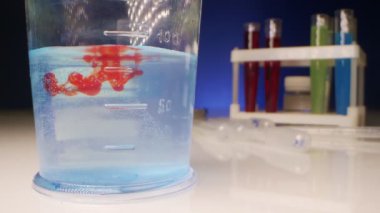  Kimyasal deneyler. Kırmızı sıvı, test tüpündeki temiz bir sıvıda çözünür.