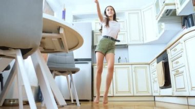 Güzel kız dansçı evde, mutfakta neşeyle dans ediyor.