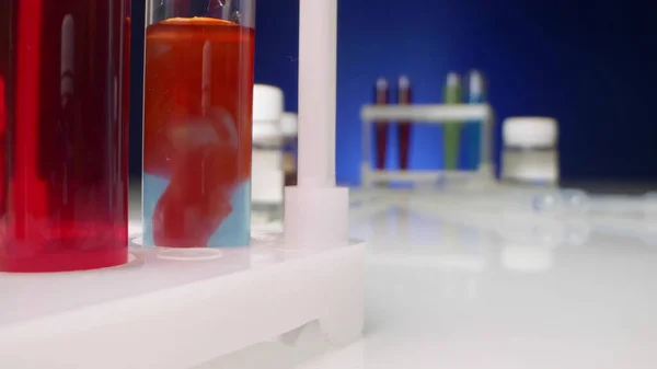 Chemische Experimente. rote Flüssigkeit löst sich in einer klaren Flüssigkeit im Reagenzglas — Stockfoto
