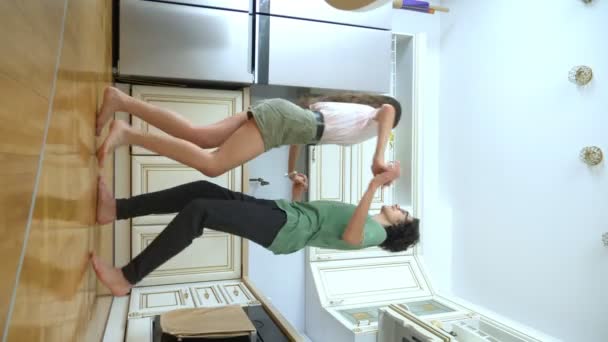 Verticale video. grappig guy en meisje dansen samen thuis in de keuken — Stockvideo