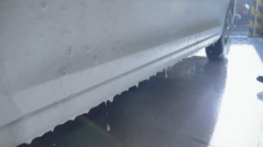 Araba yıkama yerindeki arabadan kalın beyaz köpük damlıyor.