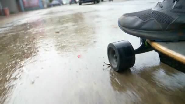 Detailní záběr. mans nohy jezdit na elektrickém skateboardu na mokrém asfaltu ulic města — Stock video
