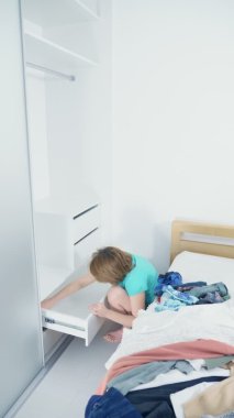 Kadın evde temizlik yapıyor. Dolaptaki tozları kırmızı bir bezle siliyor.