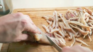 Yakın plan. Erkek eli, tahta kesme tahtasının üzerinde kaynamış domuz kulağı gibi kesilmiş.