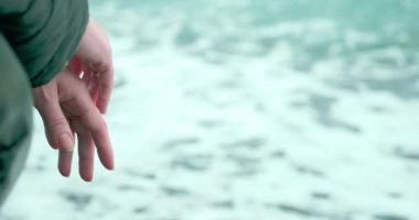 Denizin arka planında bir kadın eli ceketinin içinde. Boşluğu kopyala