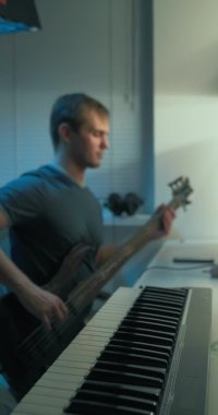 dikey video. Adam evde, monitörün önündeki masada elektronik müzik yazıyor.