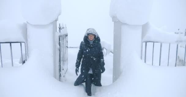 Bir kadın geçitten ayrılarak kar yığınlarının arasından geçiyor. — Stok video