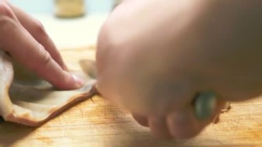 Yakın plan. Erkek eli, tahta kesme tahtasının üzerinde kaynamış domuz kulağı gibi kesilmiş.