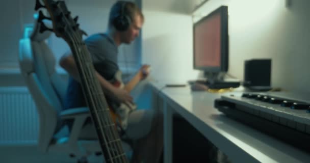 Чоловік пише електронну музику вдома за столом перед монітором — стокове відео