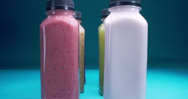 Mavi arka planda çok renkli meyve ve sebze suları olan şişelerin detaylı yakın çekimi.