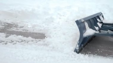 Yakın çekim traktör kovası yoldan kar topluyor.