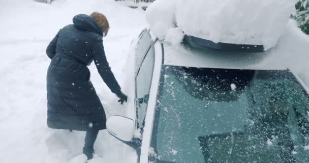Kobieta kopie śnieg stopami wokół zaparkowanego samochodu — Wideo stockowe