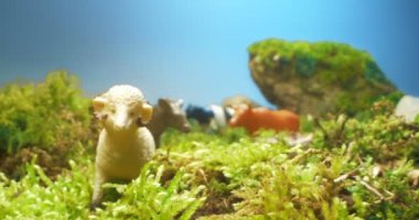 Yosun ve çimenlikteki boynuzlu evcil hayvanların plastik heykellerinin detaylı bir yakın çekimi.