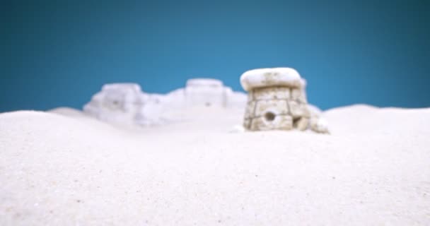 Dettaglio estremo primo piano di dolmen miniatura in sabbia bianca su sfondo blu — Video Stock