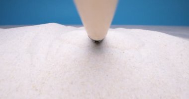 Detaylı aşırı yakın çekim, mini tırmık mavi arka planda beyaz kumu gevşet