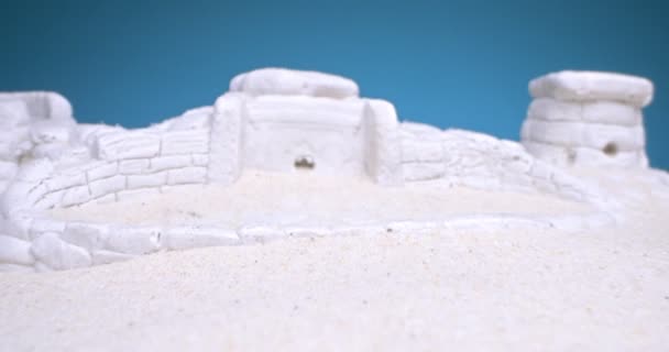 青い背景に白い砂の中にあるドルマンのミニチュアの詳細 — ストック動画