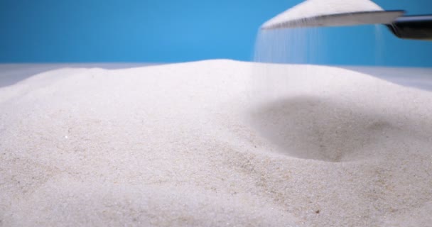 Gedetailleerde extreme close-up graven wit zand met mini schop op blauwe achtergrond — Stockvideo