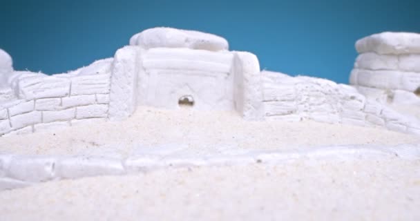 Dettaglio estremo primo piano di dolmen miniatura in sabbia bianca su sfondo blu — Video Stock