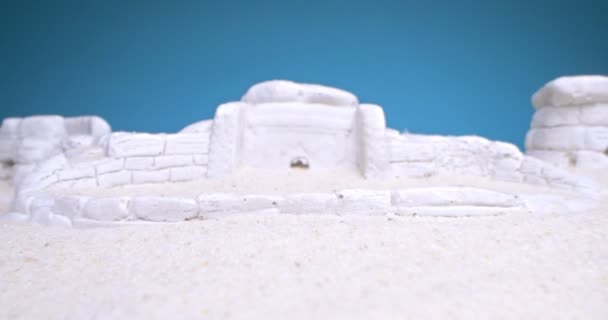 Dettaglio estremo primo piano di dolmen miniatura in sabbia bianca su sfondo blu — Video Stock