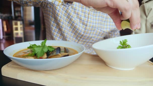 Close-up, someone eats tom yam with mussels with a spoon from a white plate — Video Stock