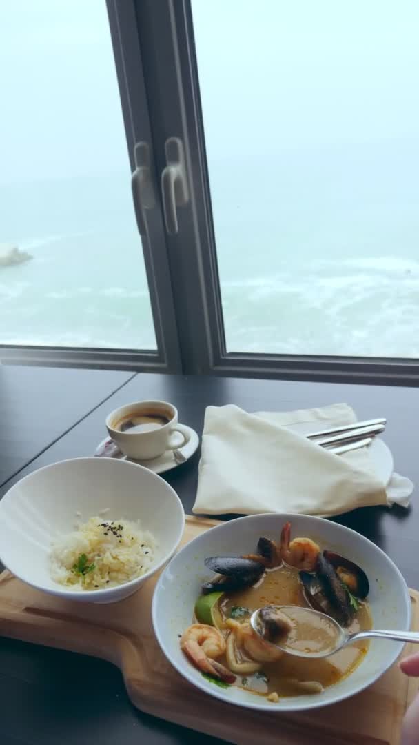 Vertikální video. zblízka, někdo jí Tom Yam s mušlemi s lžící z bílého talíře — Stock video
