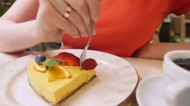 Yakın plan. Bir parça vejetaryen mango turtası yiyen bir kadın.