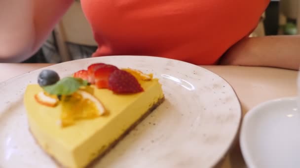 Primer plano. mujer comiendo con un tenedor un pedazo de pastel de mango vegano — Vídeos de Stock