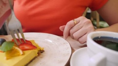 Yakın plan. Bir parça vejetaryen mango turtası yiyen bir kadın.