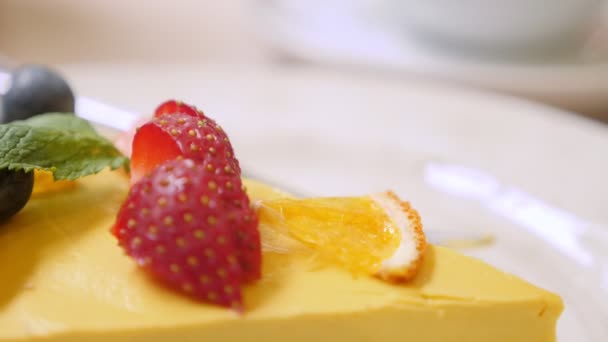 Close-up van een stuk rauwe mango passievruchtentaart met aardbeien en bosbessen — Stockvideo