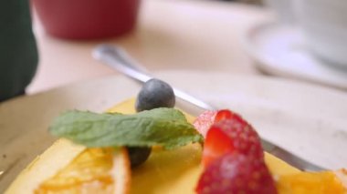 Çilek ve böğürtlenlerle süslenmiş bir dilim çiğ mango ve tutkulu meyveli kekin yakın çekimi.