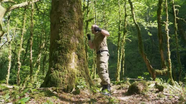Süper yavaş çekim. Ormanda erkek boksör eğitimi, büyük bir ağacın gövdesinde boks. — Stok video
