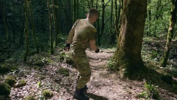 Гумор. спортивний чоловік в одязі хакі обманює смішний біг і стрибає через ліс — стокове відео