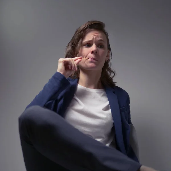 Cool business woman in a jacket sitting in a chair on a dark background - Stok İmaj